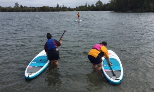 Two people are standing on paddle boards in the water.