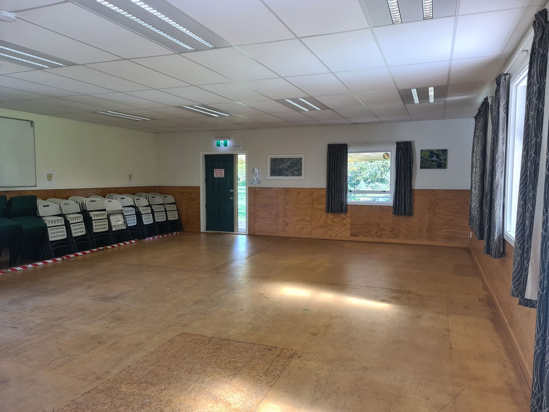 A large empty room with a wooden floor and a door.