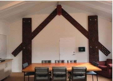 A room with a table and chairs and a large wooden beam on the wall