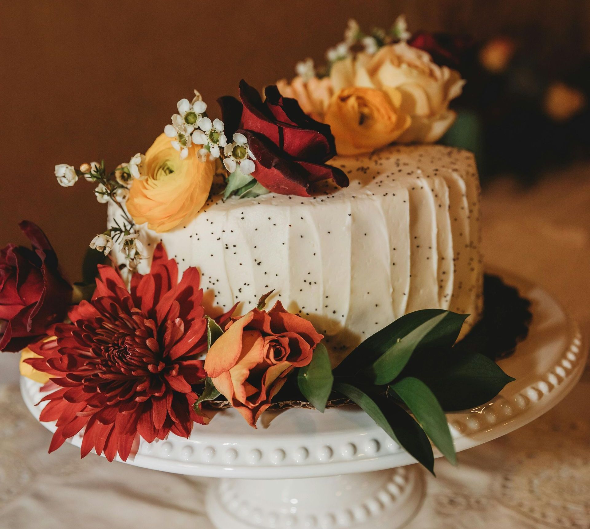 A white wedding cake is sitting on top of a wooden table.