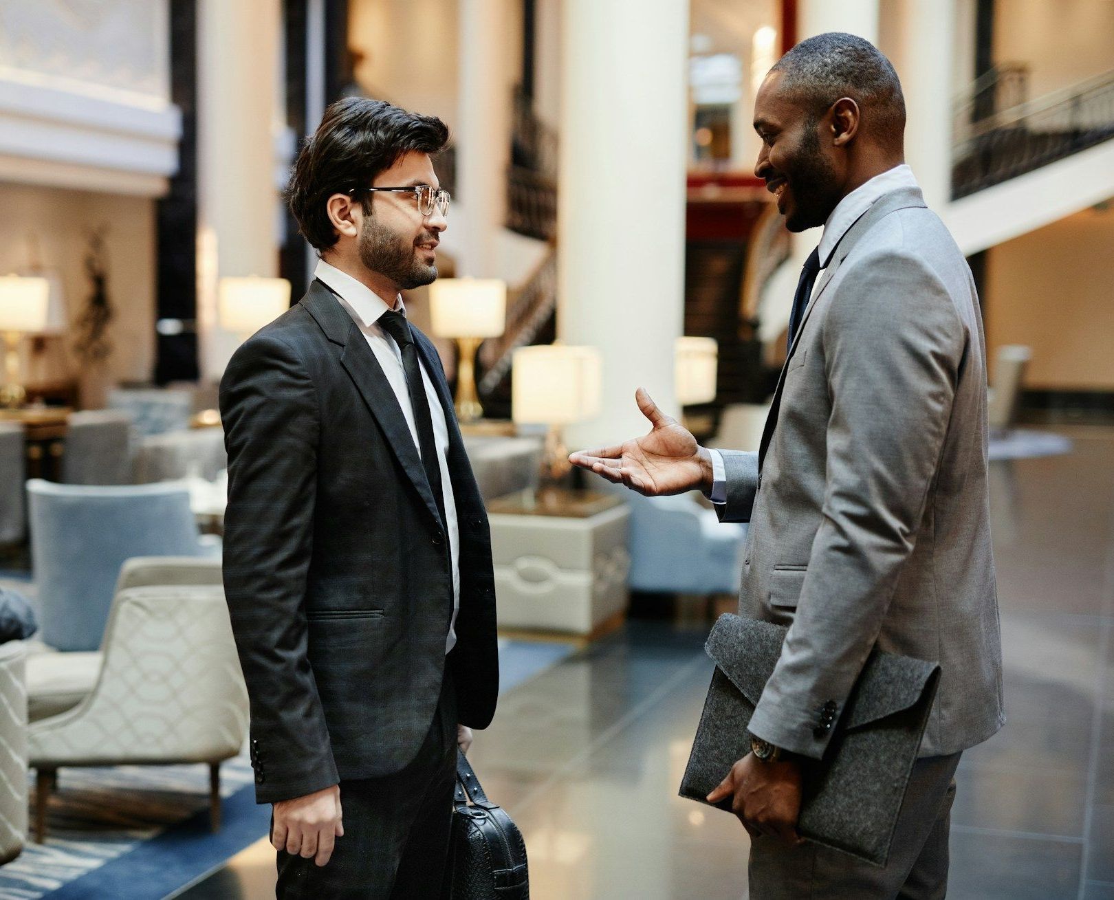 Two men in suits are talking to each other in a lobby.