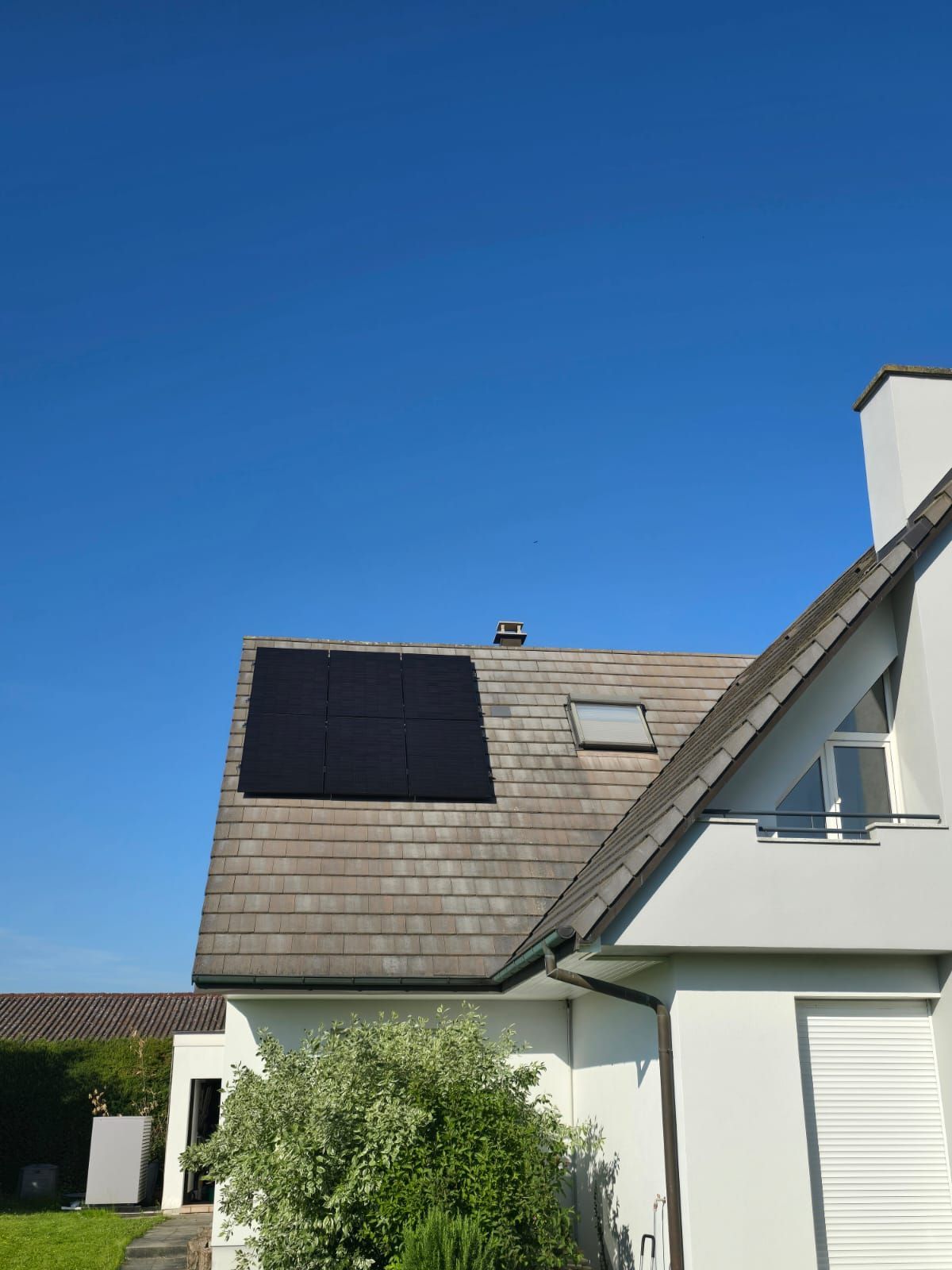 Une maison avec des panneaux solaires sur le toit et un ciel bleu en arrière-plan.