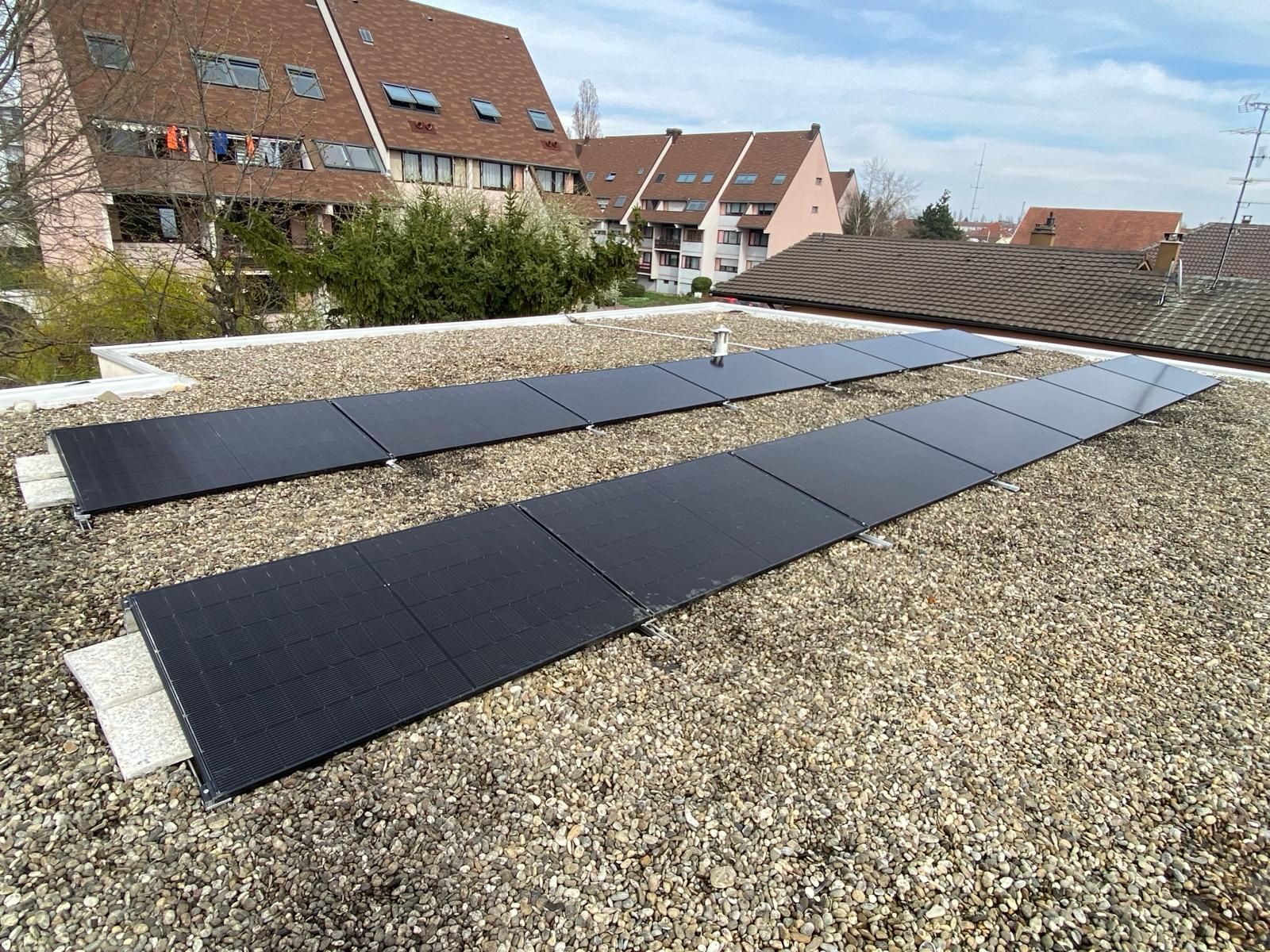 Une rangée de panneaux solaires est posée sur un toit en gravier.