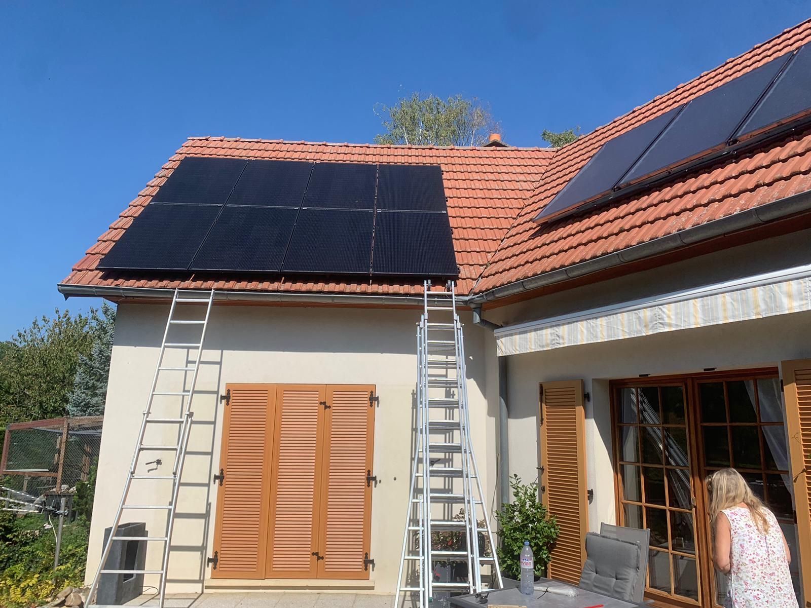 Une femme se tient devant une maison avec des panneaux solaires sur le toit.