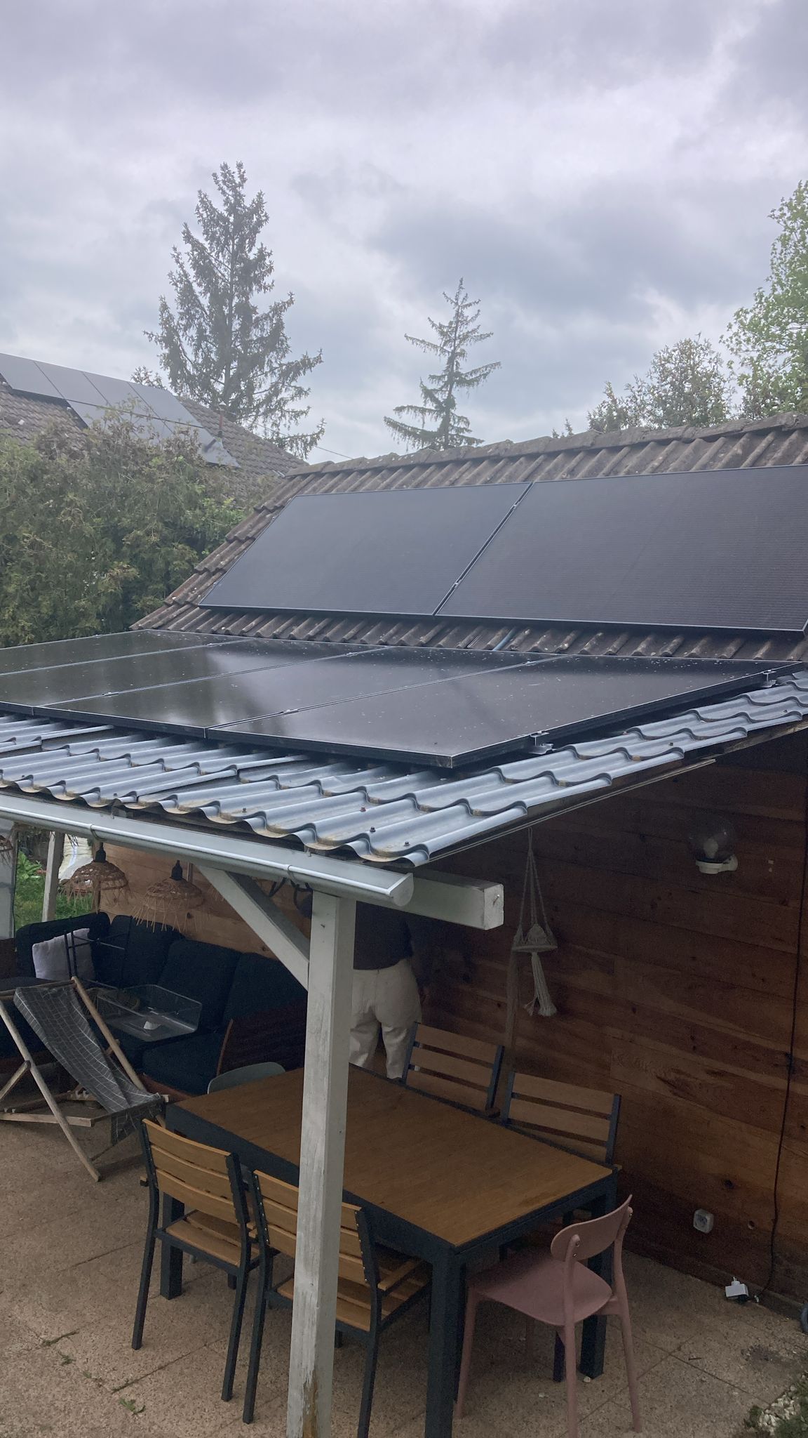 Un patio avec une table et des chaises sous un toit avec panneaux solaires.