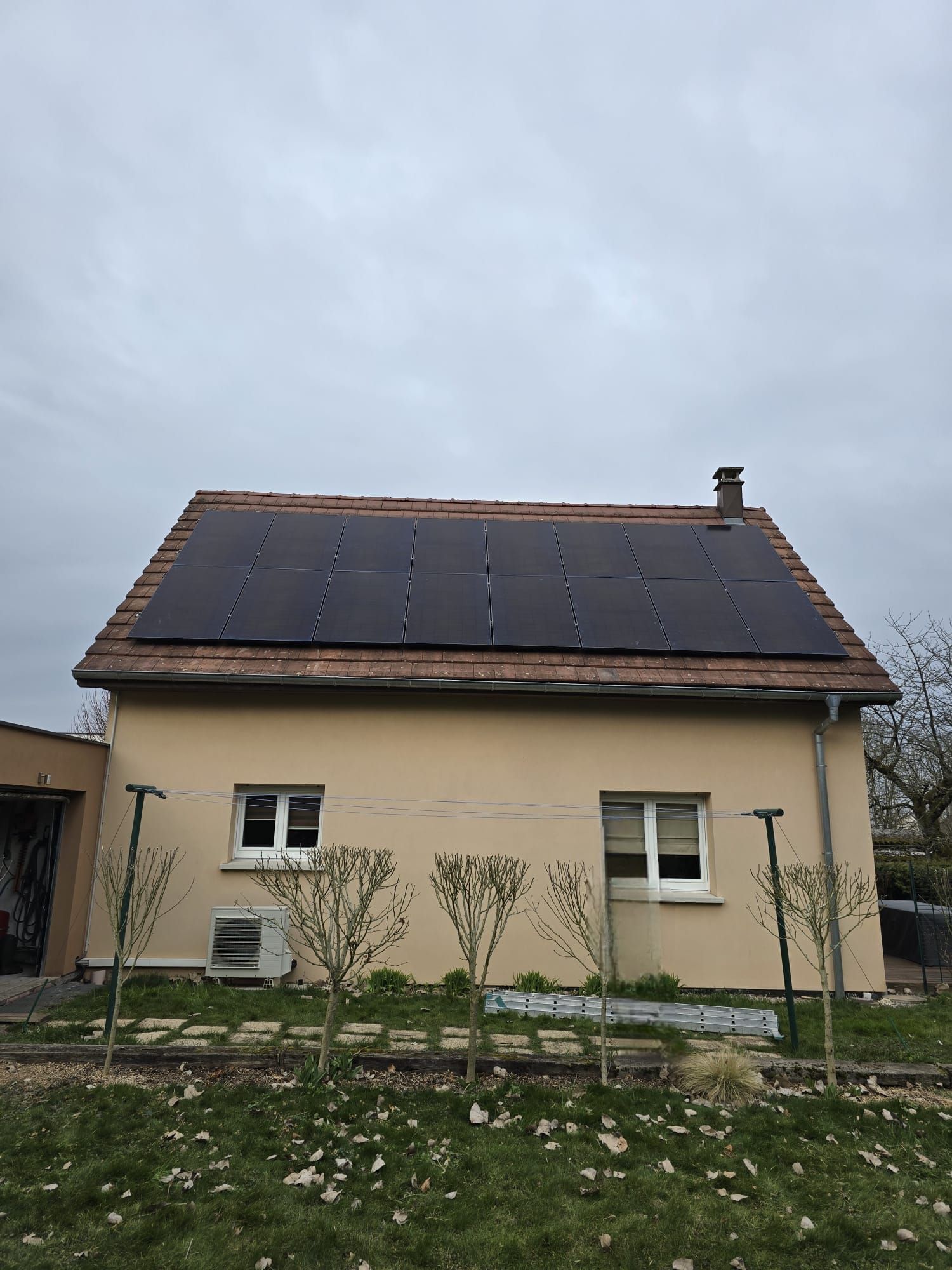 Un homme se tient devant une maison avec des panneaux solaires sur le toit.