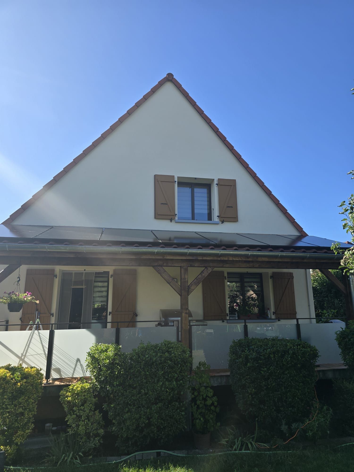 Une maison blanche avec des volets marron aux fenêtres