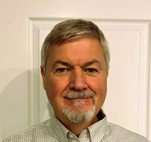 A man in a striped shirt is smiling for the camera.