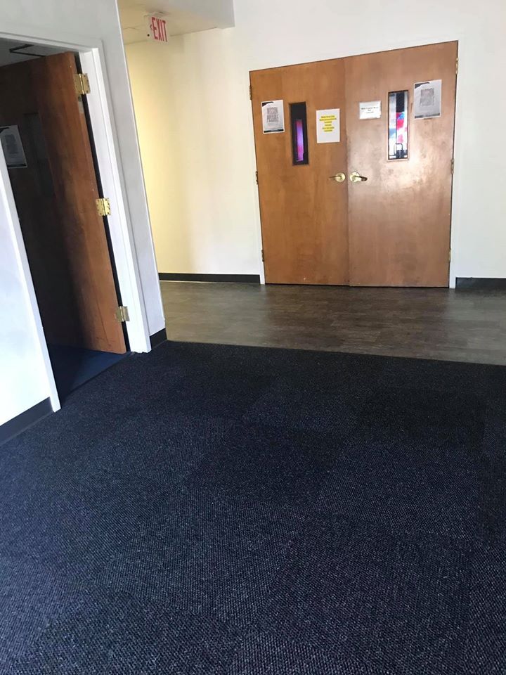 An empty room with a black carpet and wooden doors.