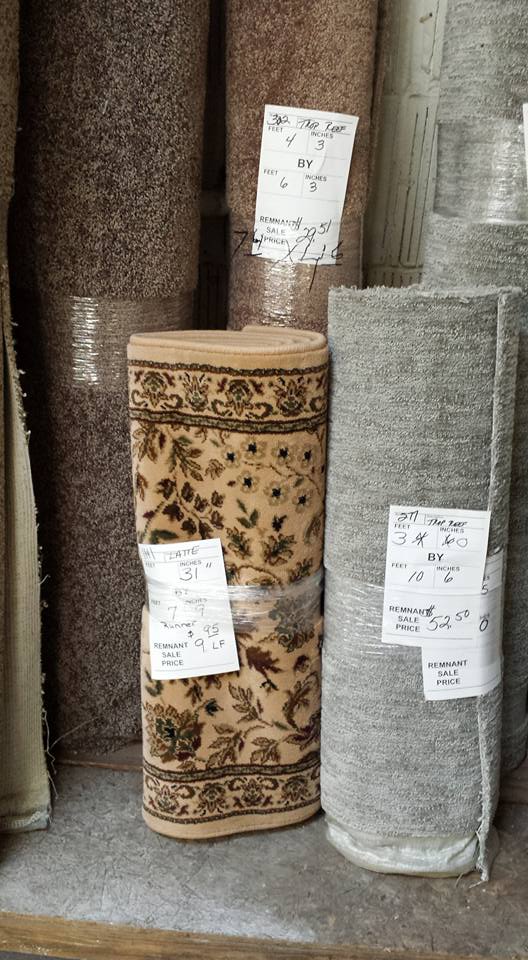 Three rolls of carpet are stacked on top of each other on a shelf.