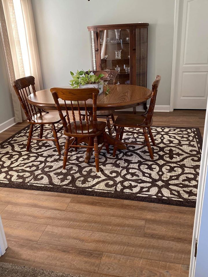 A dining room with a table and chairs and a rug.