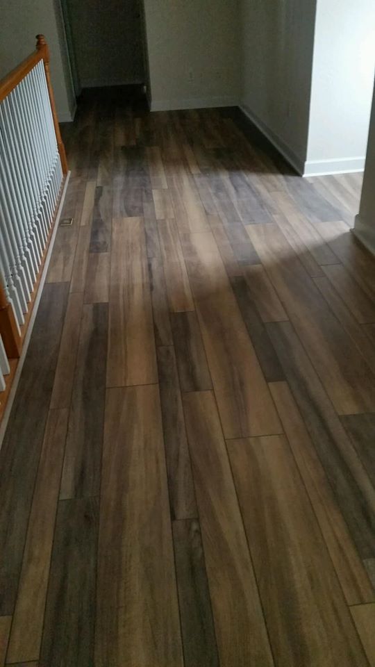 A hallway with a wooden floor and stairs in a house.