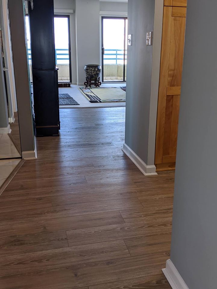 A hallway with hardwood floors leading to a living room.