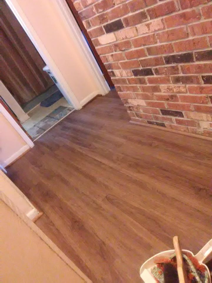 A hallway with a wooden floor and a brick wall.