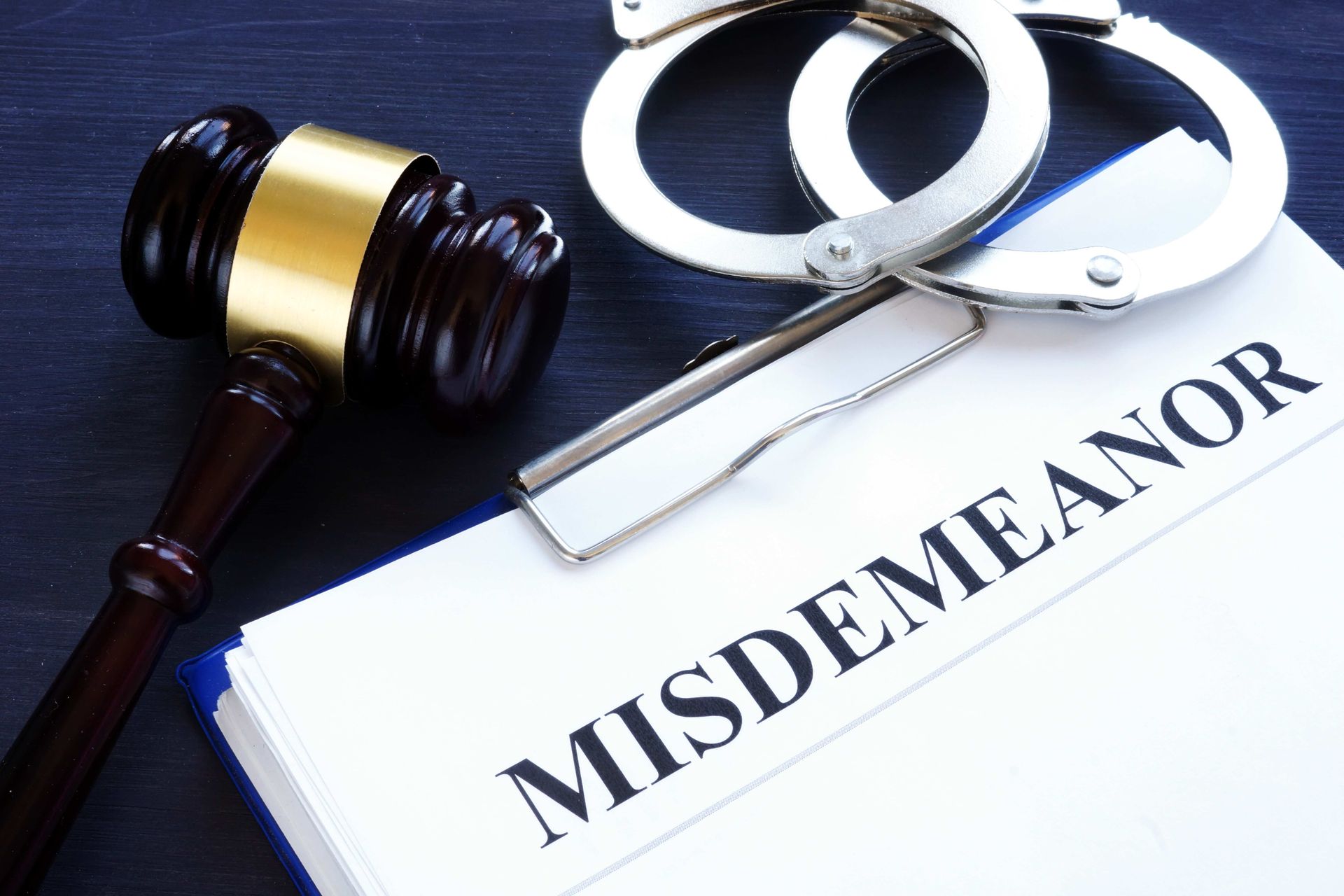 a misdemeanor is written on a clipboard next to a judge 's gavel and handcuffs