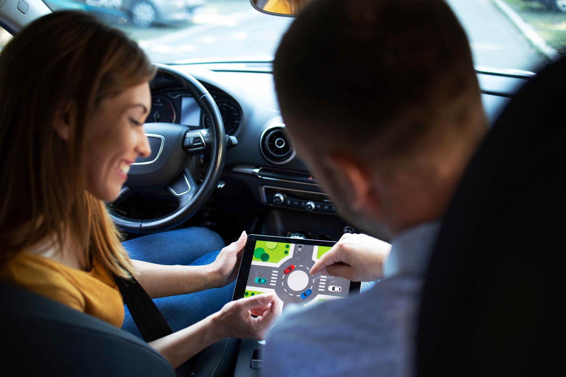 a man and a woman are sitting in a car looking at a tablet