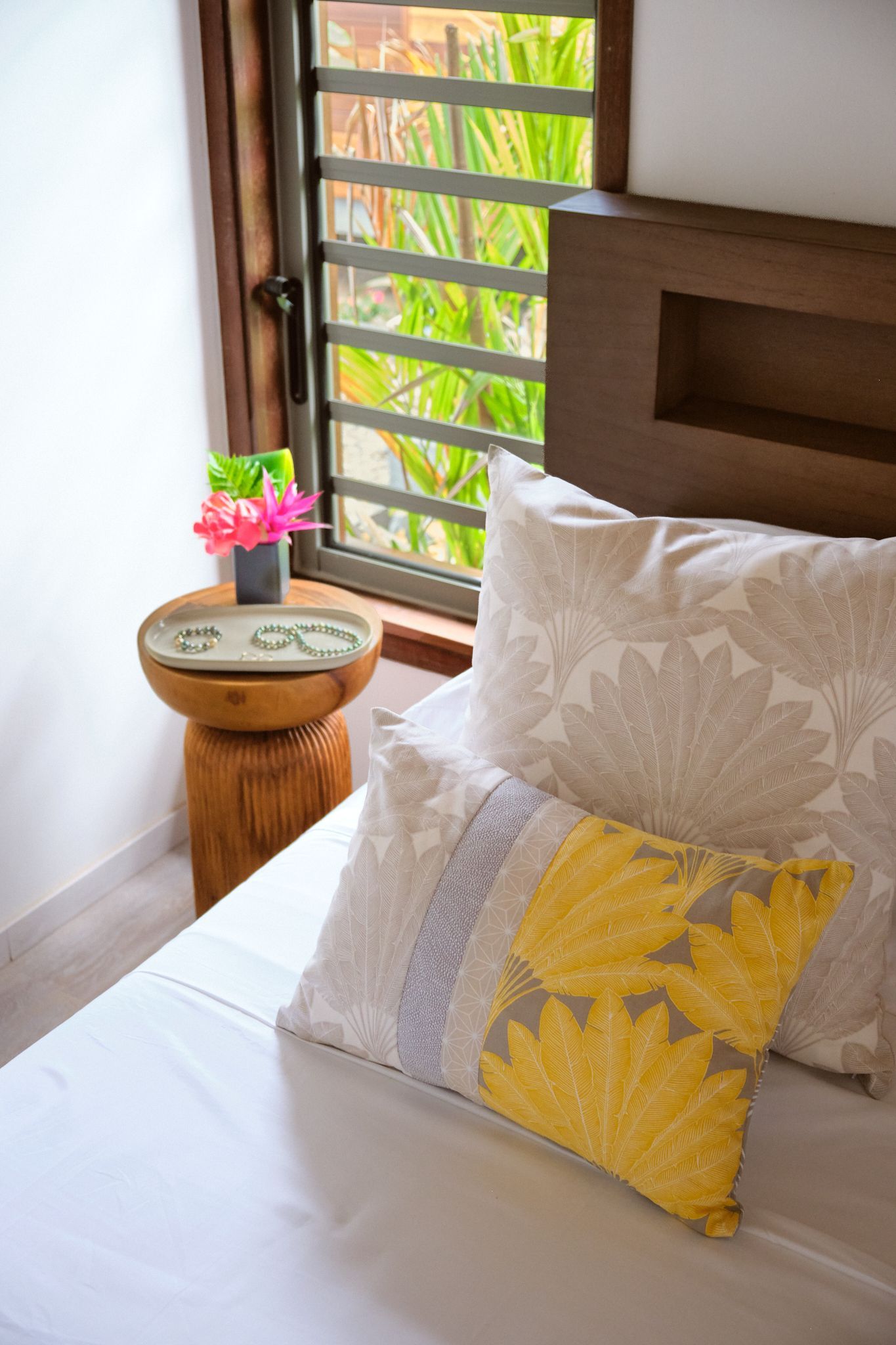A bedroom with a bed , pillows , a table and a window.