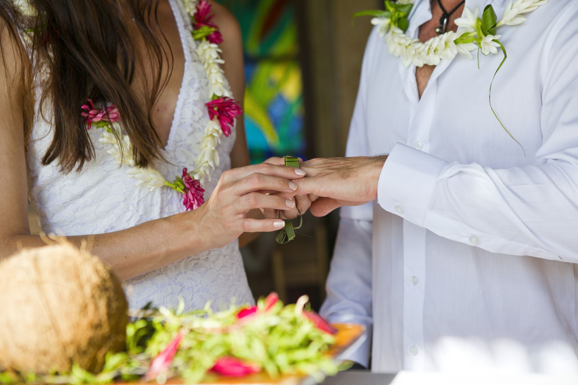 A bride and groom are putting their wedding rings on each other 's fingers.