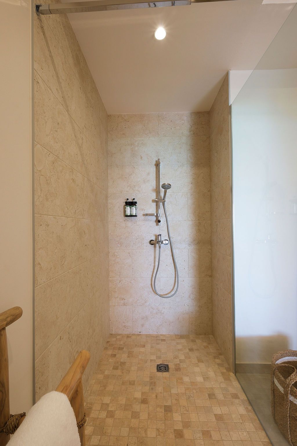 A bathroom with a walk in shower and a chair.
