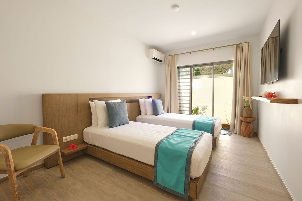 A hotel room with two beds , a chair and a television.