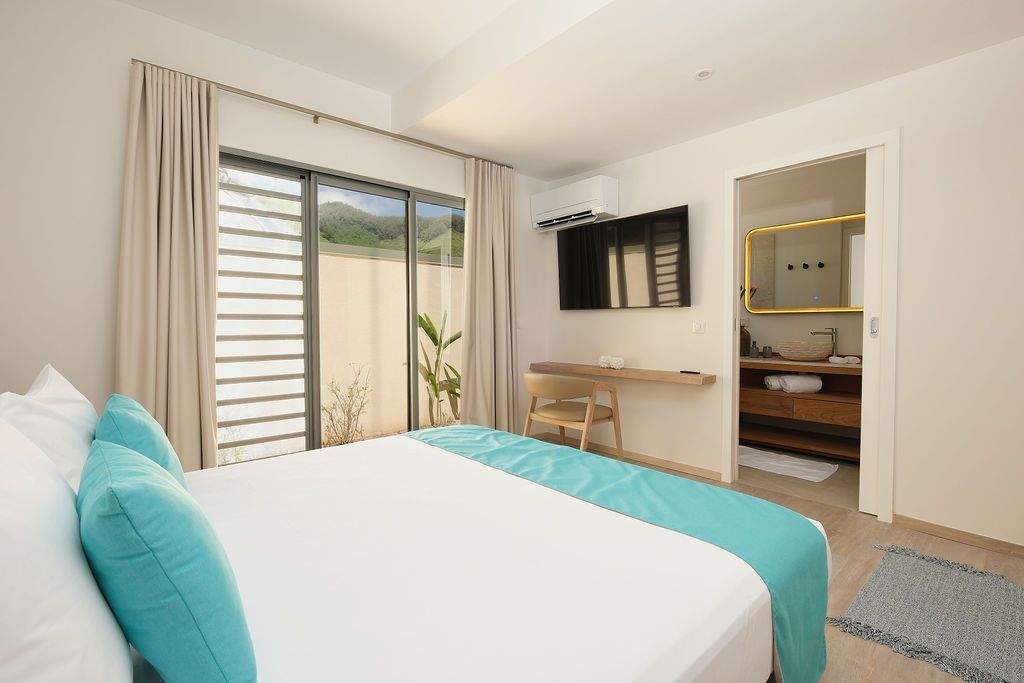 A bedroom with a large bed and a sliding glass door leading to a bathroom.