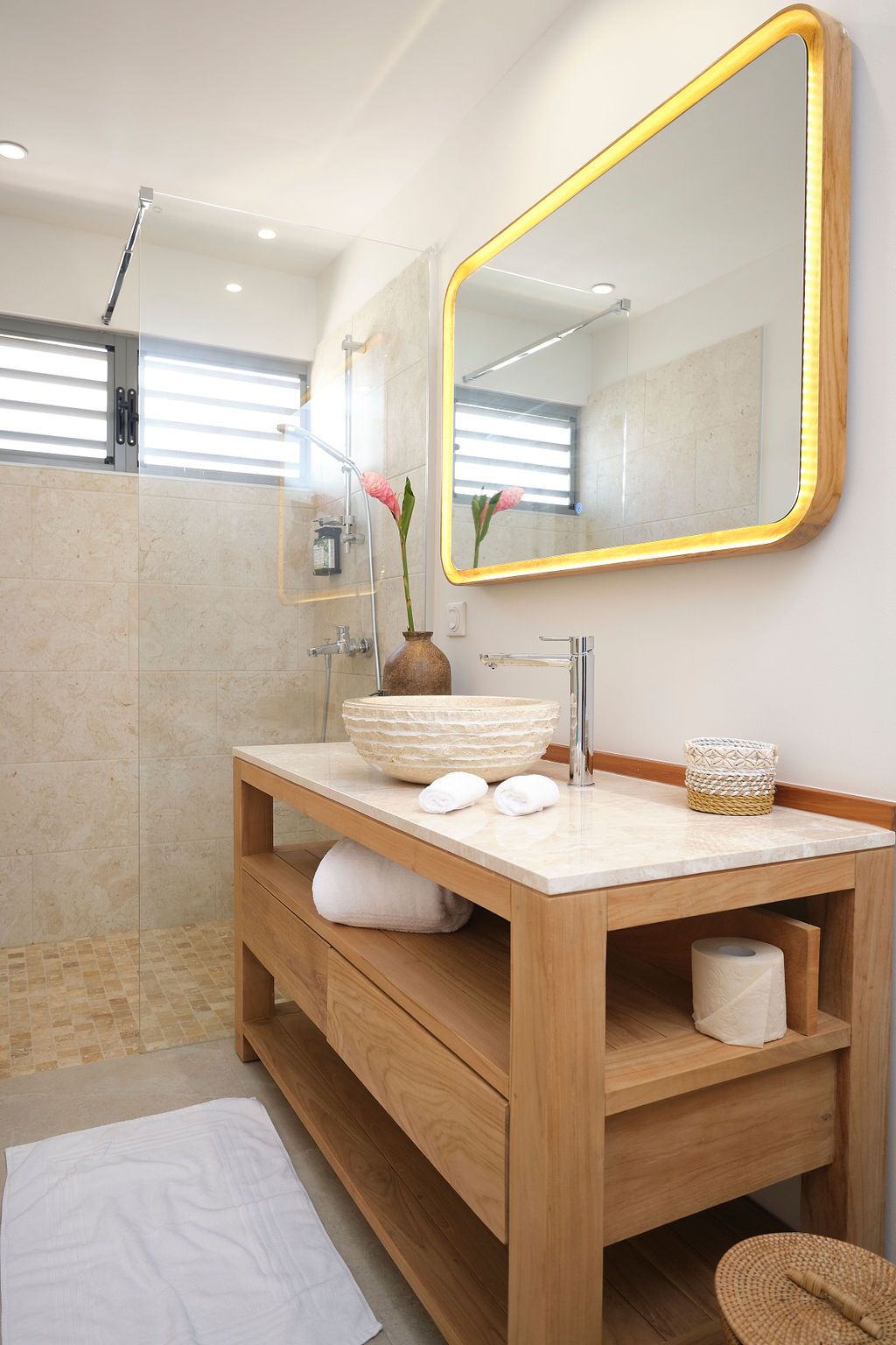 A bathroom with a sink , mirror and walk in shower.