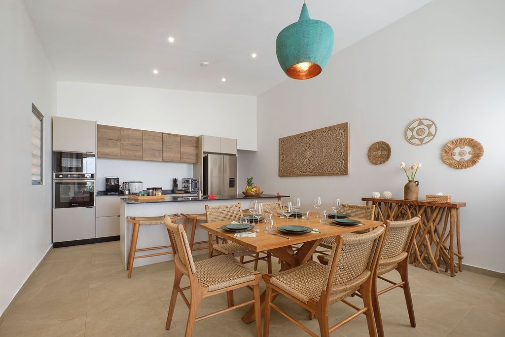 A dining room with a table and chairs in front of a kitchen.