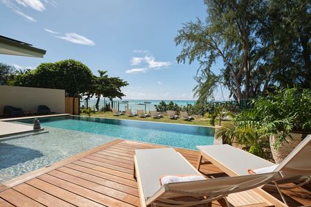 A large swimming pool is surrounded by chairs and a wooden deck.