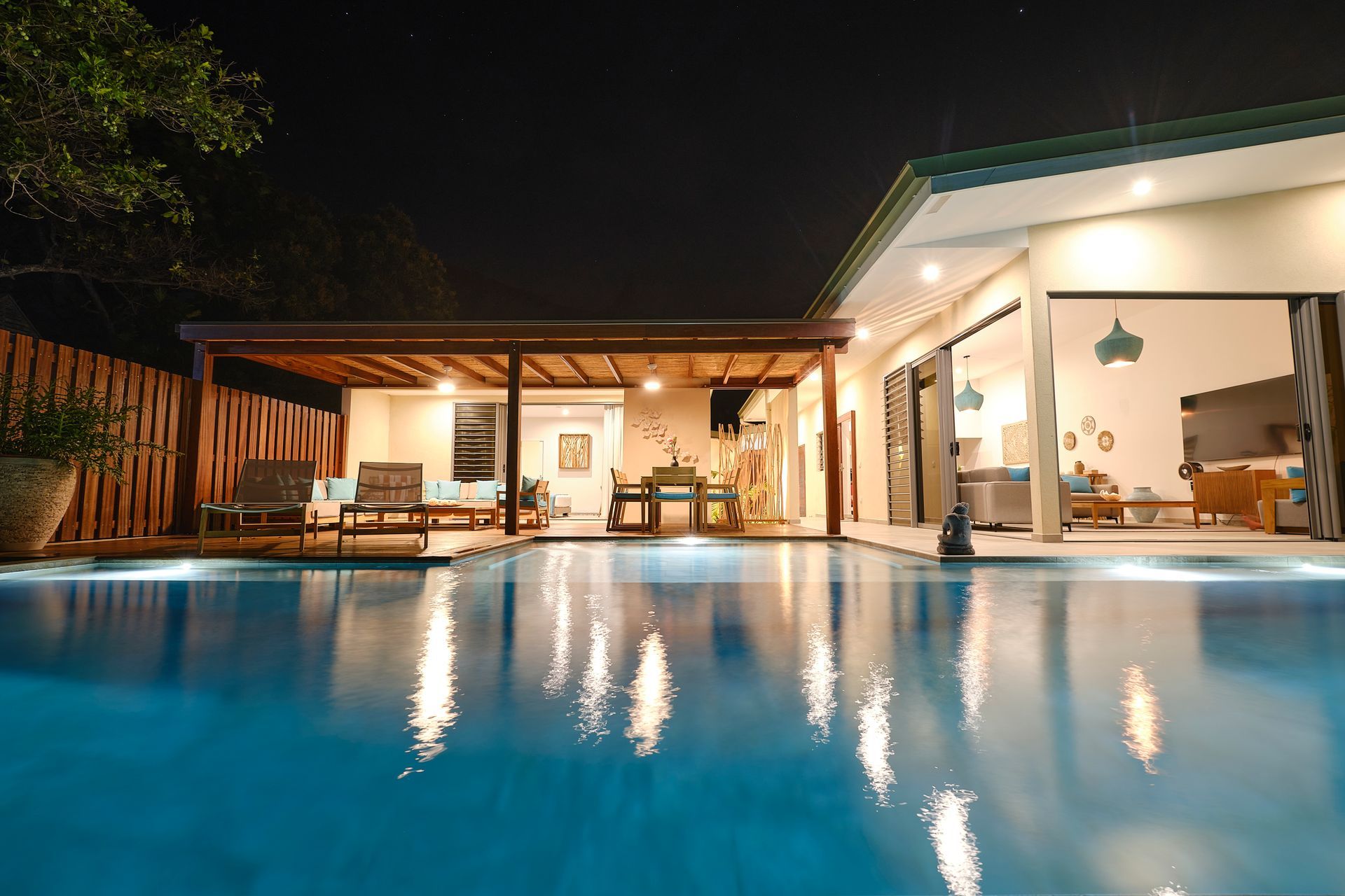 A large swimming pool is in front of a house at night.