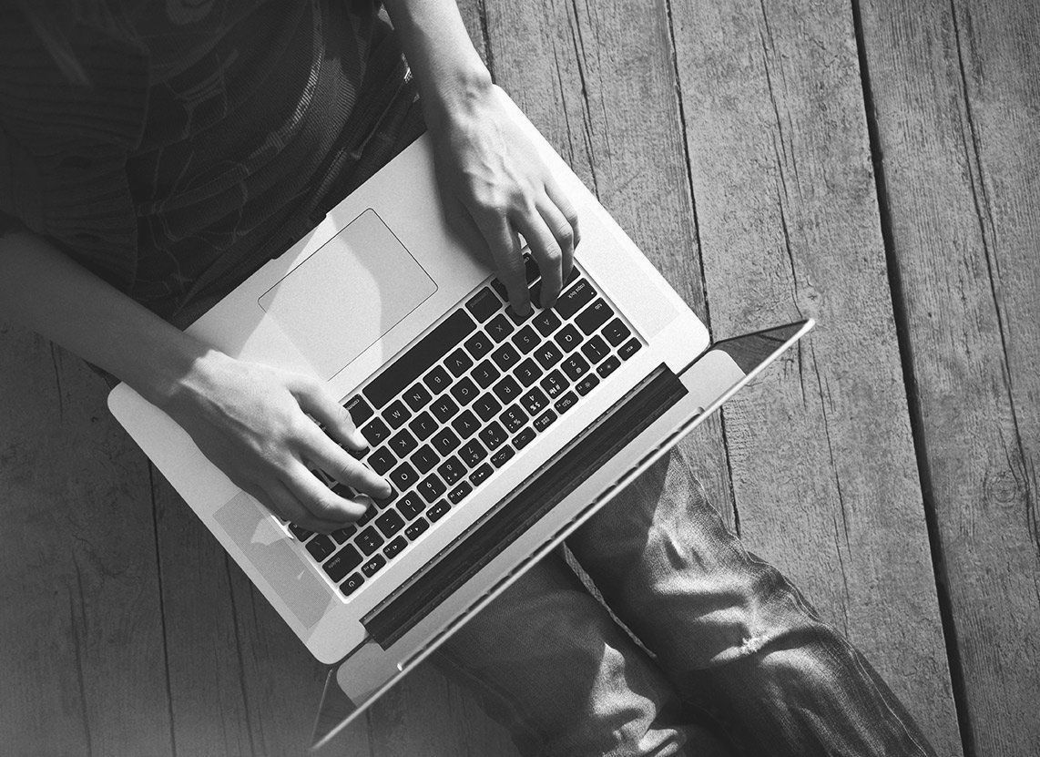 Une personne tape sur un ordinateur portable sur un plancher en bois.