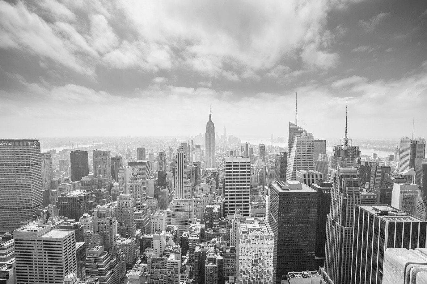Une photo en noir et blanc d'un horizon de ville avec un ciel nuageux en arrière-plan.