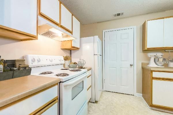 Brick building with white columns, door, and a brick walkway. Green lawn.