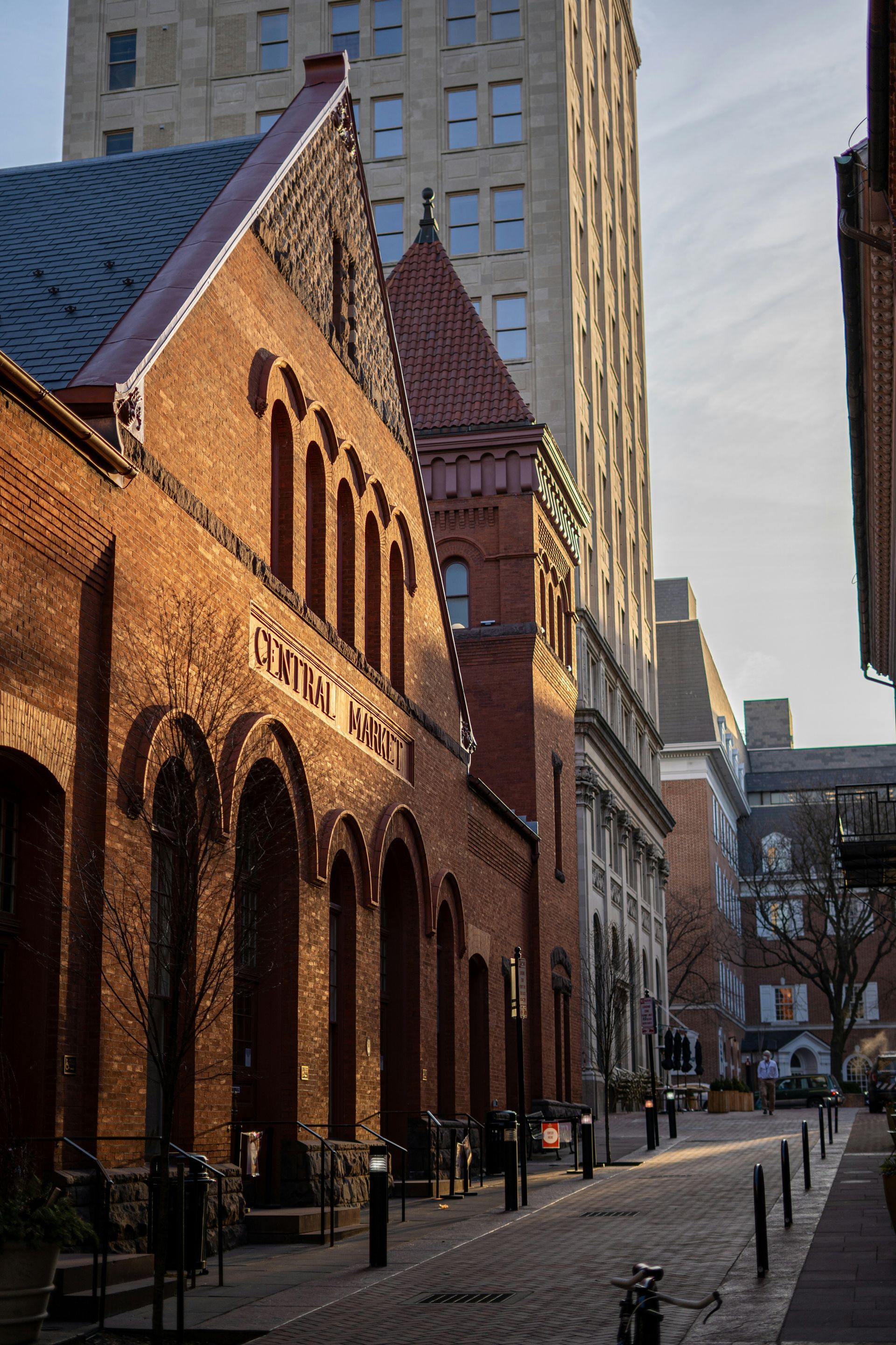 Red brick buildings and cobblestone street with a tall skyscraper in the background.