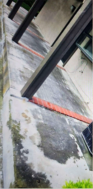 A concrete walkway leading to a building with a red line on it.