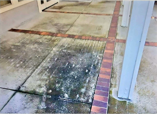 A dirty concrete walkway with a brick border