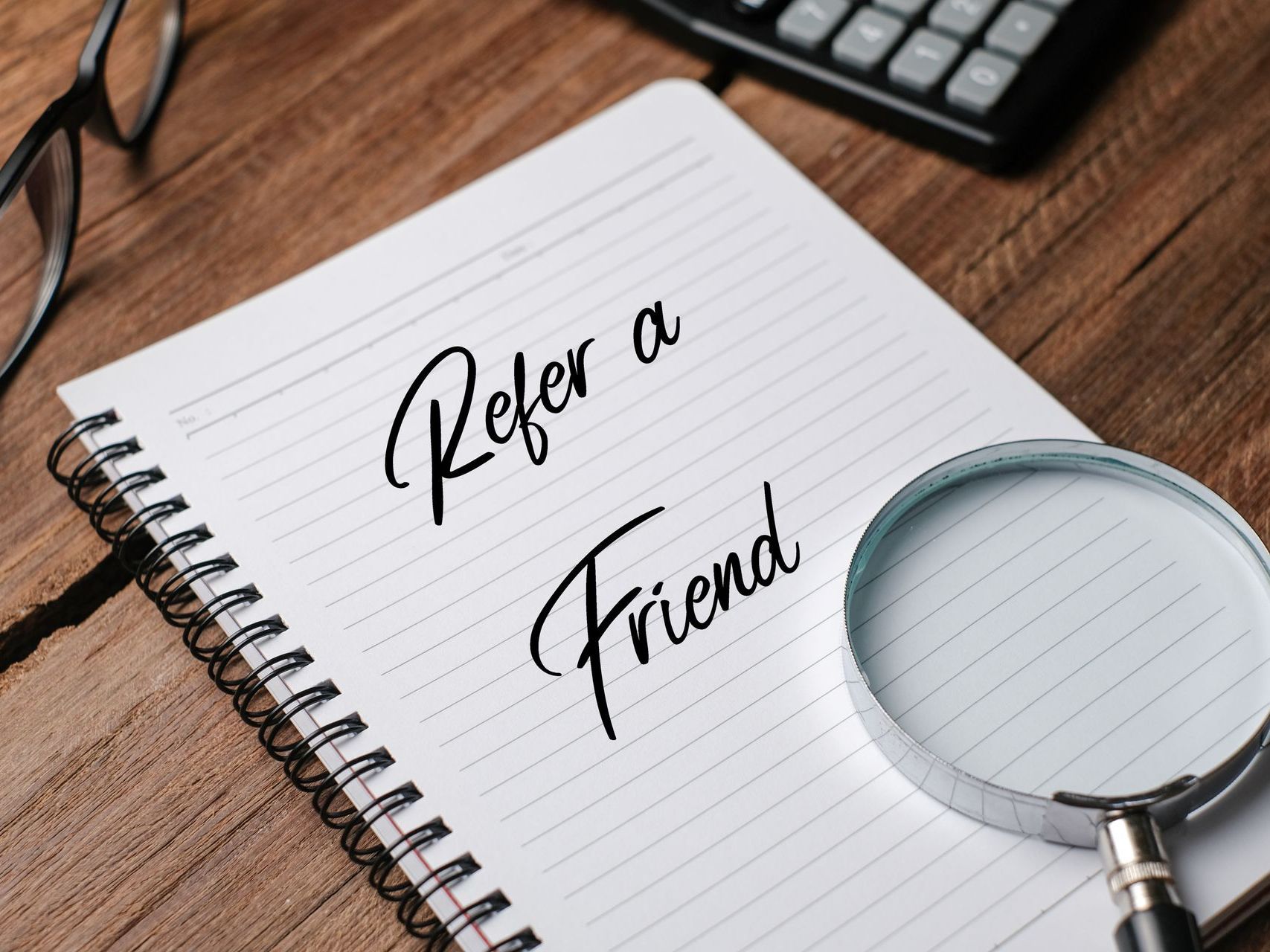 A notebook with the words refer a friend written on it