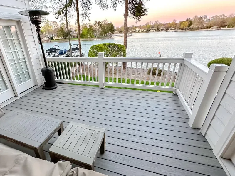 A deck with a white railing overlooking a lake