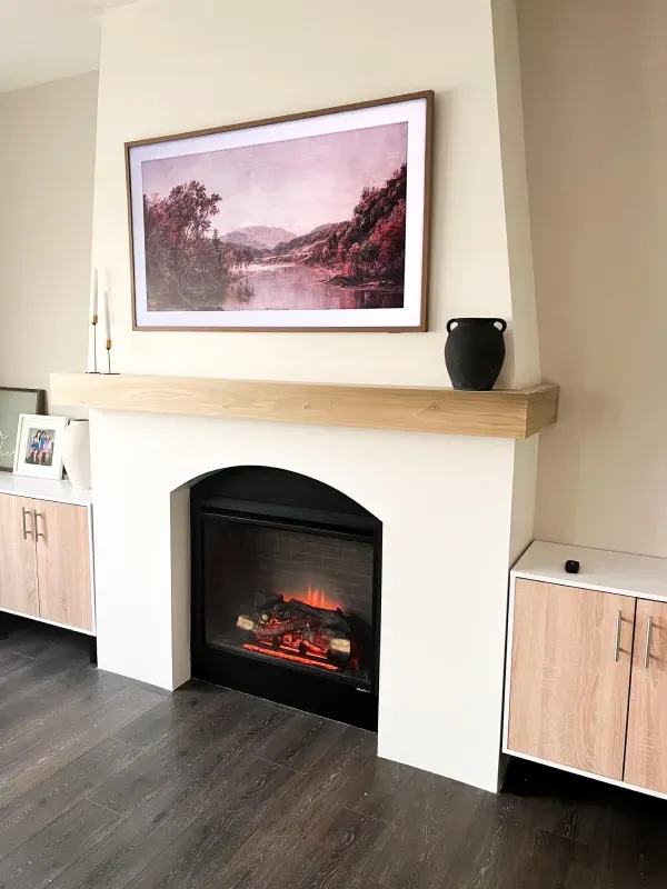 A living room with a fireplace and a picture on the wall above it.