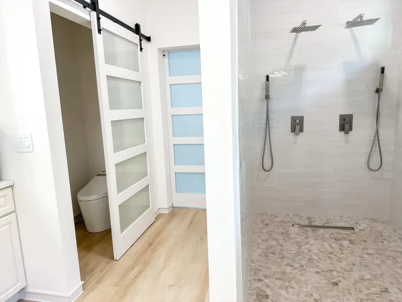 A bathroom with a toilet and a shower with a sliding barn door