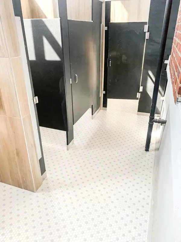 A bathroom with black and white stalls and a white floor.