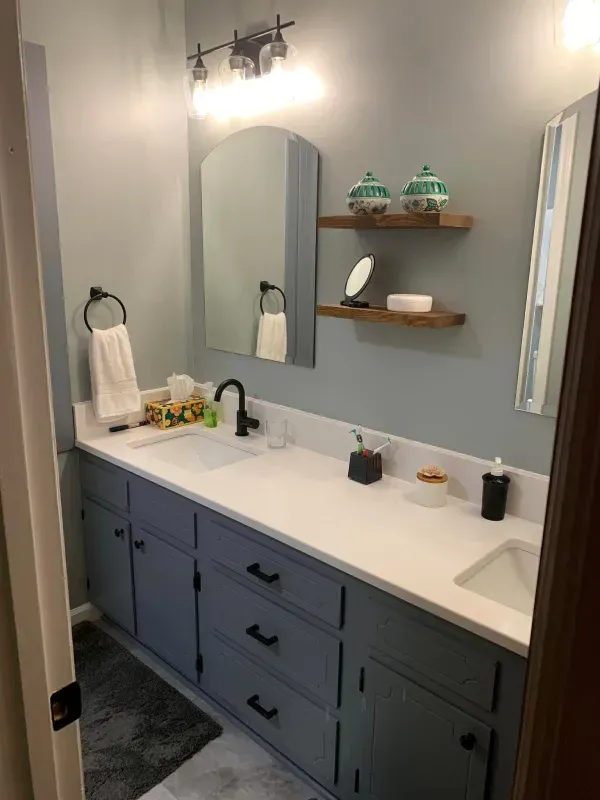 A bathroom with two sinks , a mirror and a shelf.
