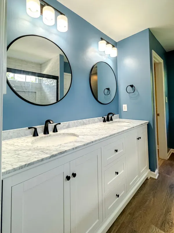 A bathroom with two sinks and two round mirrors