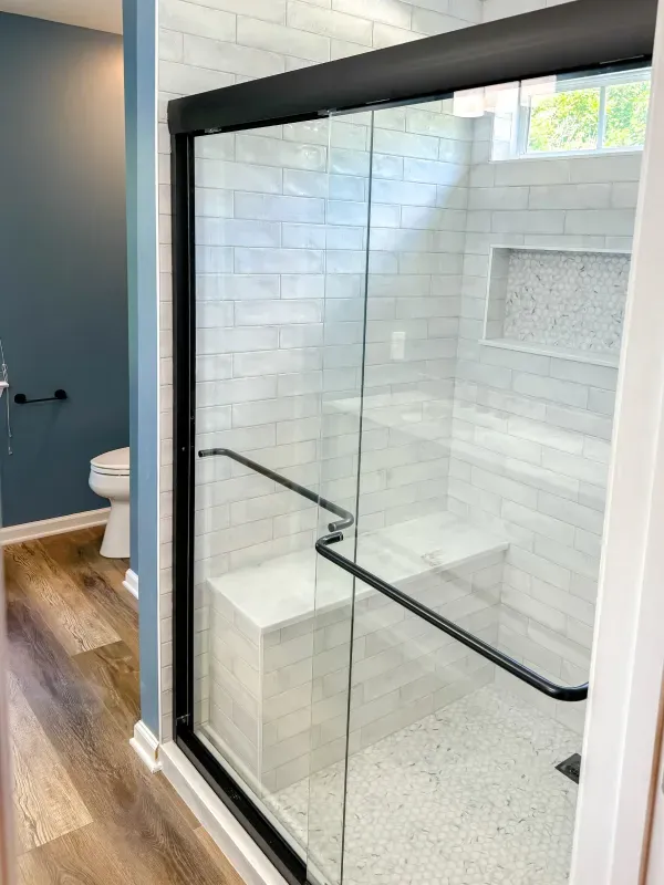 A bathroom with a sliding glass shower door and a toilet.