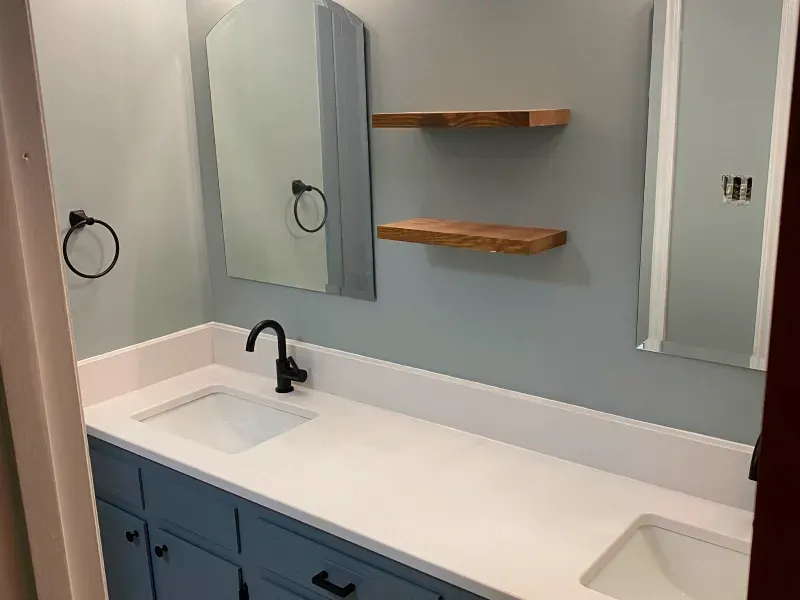 A bathroom with a sink , mirror and shelves.