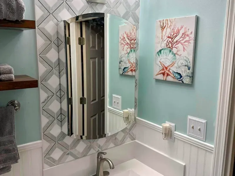 A bathroom with a sink , mirror and paintings on the wall.