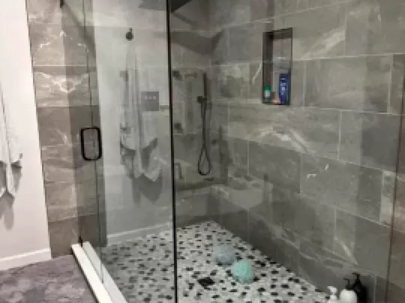 A bathroom with a walk in shower with a glass door.