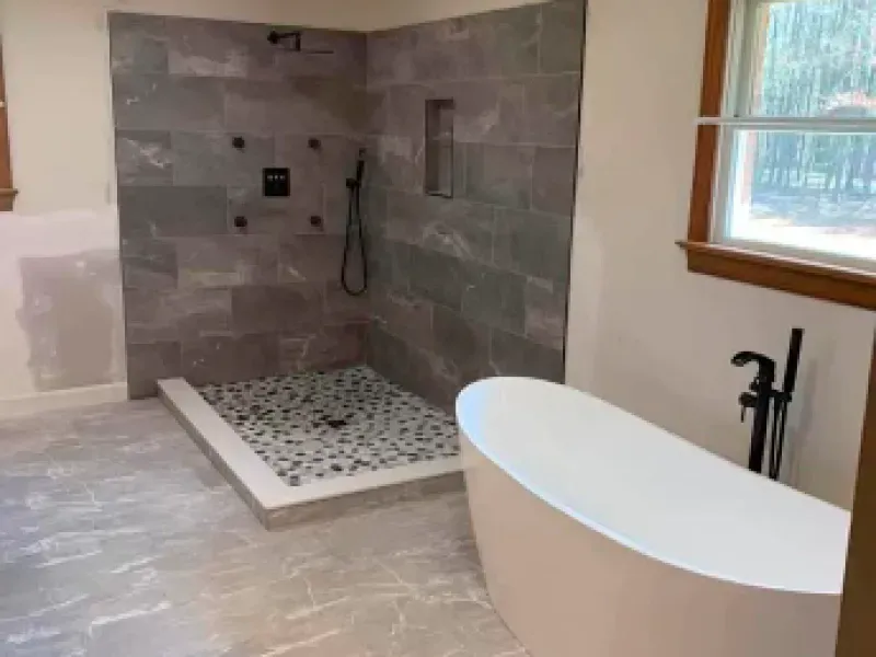 A bathroom with a tub , shower , and window.