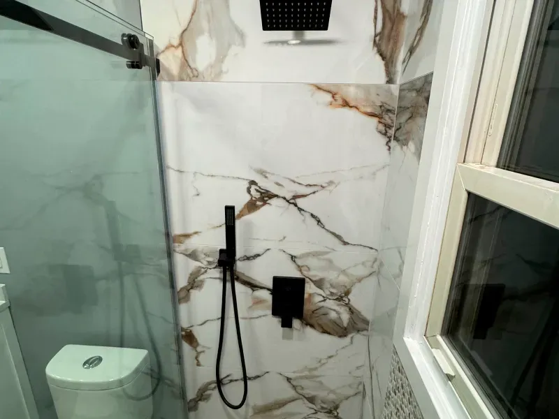 A bathroom with a toilet , shower , and window.