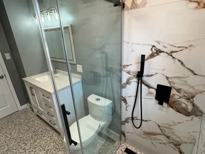 A bathroom with a toilet , sink and shower.