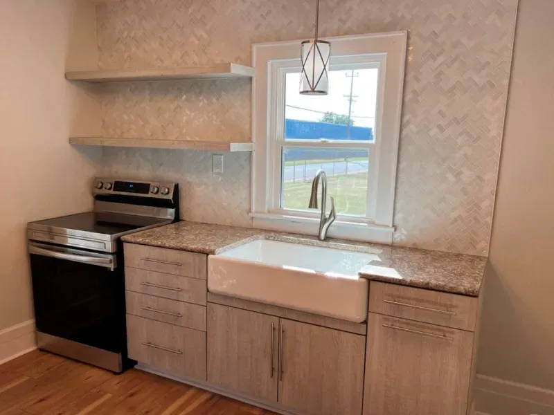 A kitchen with a stove , sink , and window.